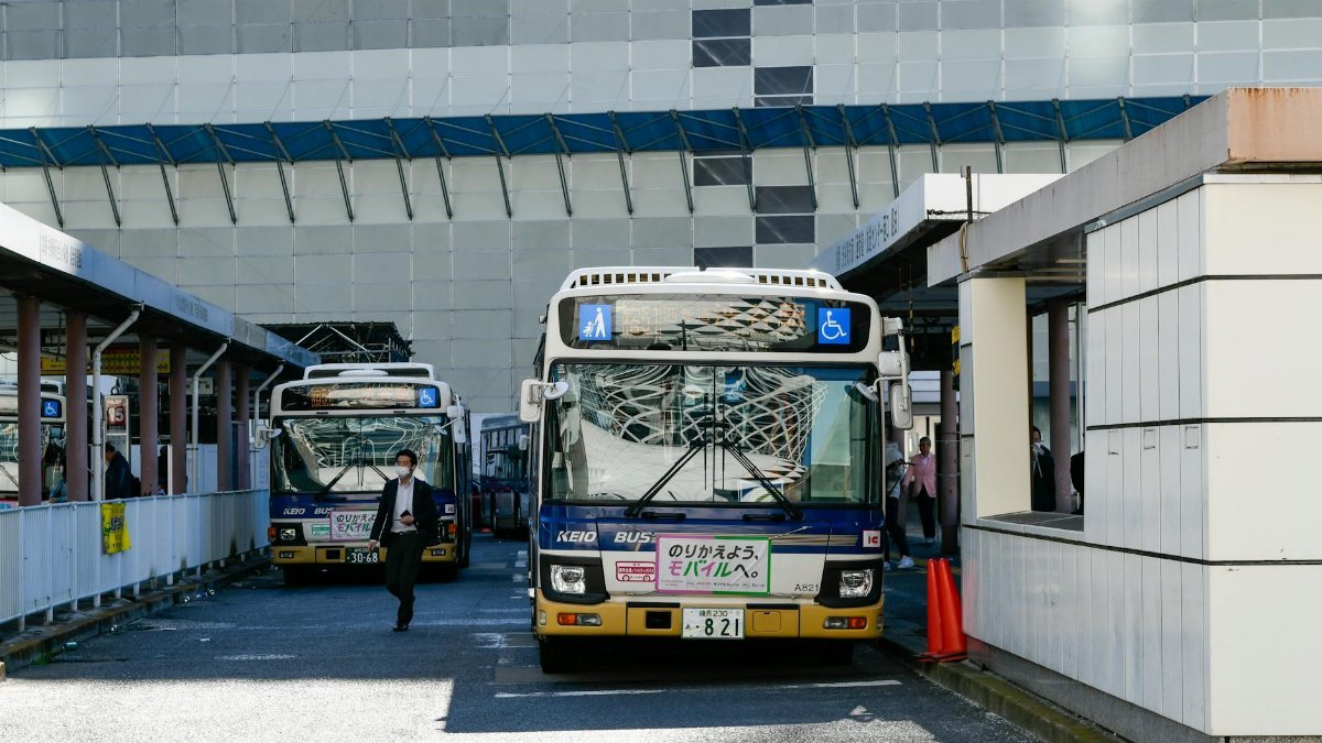 Urban scene featuring Keio buses at a bus station in Japan, showcasing public transportation and city life.