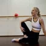 A woman in activewear rests in a bright New York yoga studio after a workout or yoga session.