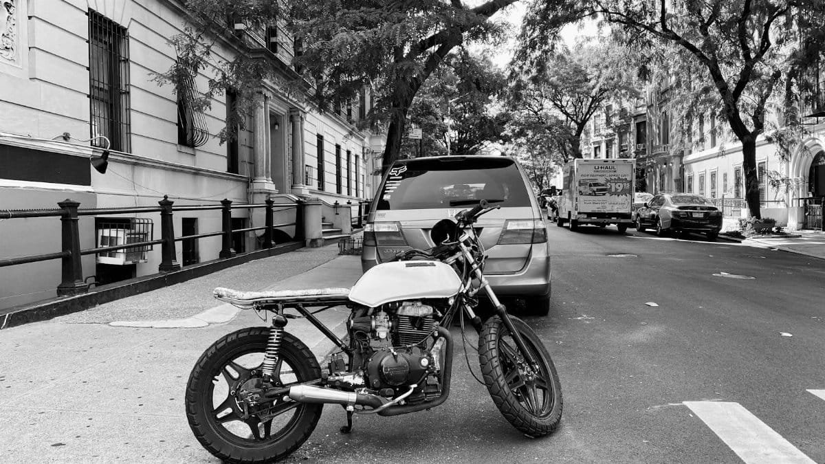 Black and white photo of a motorcycle on a quiet New York City street.