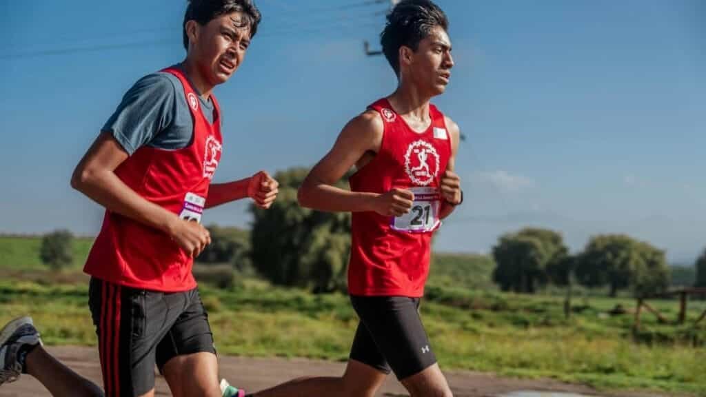 Two young men running in a marathon through the countryside, showcasing endurance and fitness.