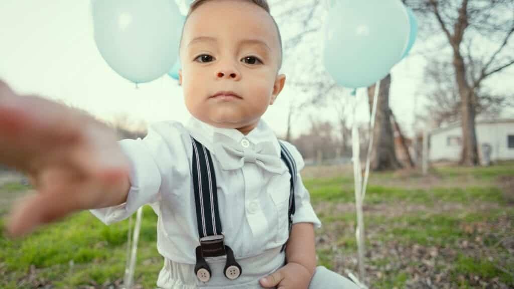 Cute toddler dressed formally with blue balloons, seated outdoors in Tulsa, Oklahoma.