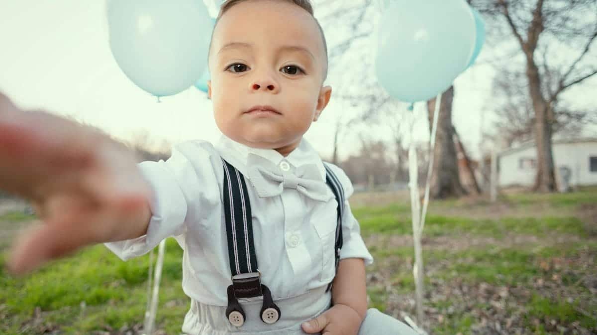 Cute toddler dressed formally with blue balloons, seated outdoors in Tulsa, Oklahoma.