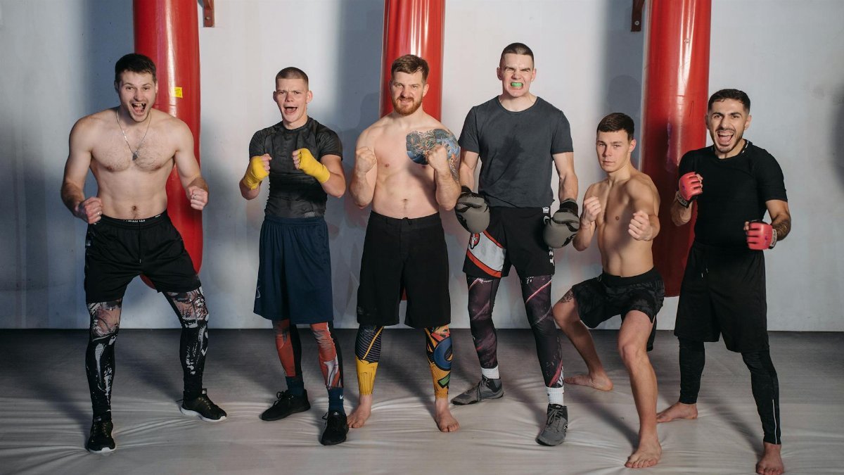 Six male fighters posing confidently in a gym, ready for training.