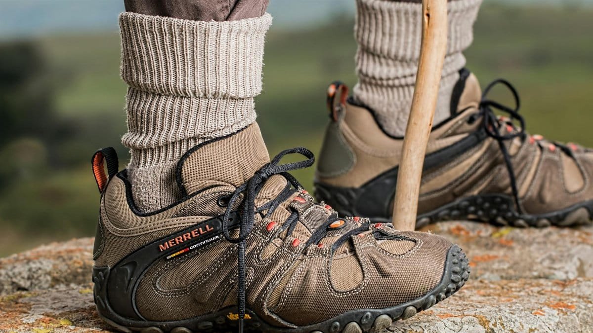 Hiking boots by Merrell on a rock edge, featuring outdoor adventure gear.