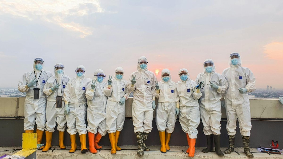 A group of healthcare workers in protective gear standing outside during sunset.