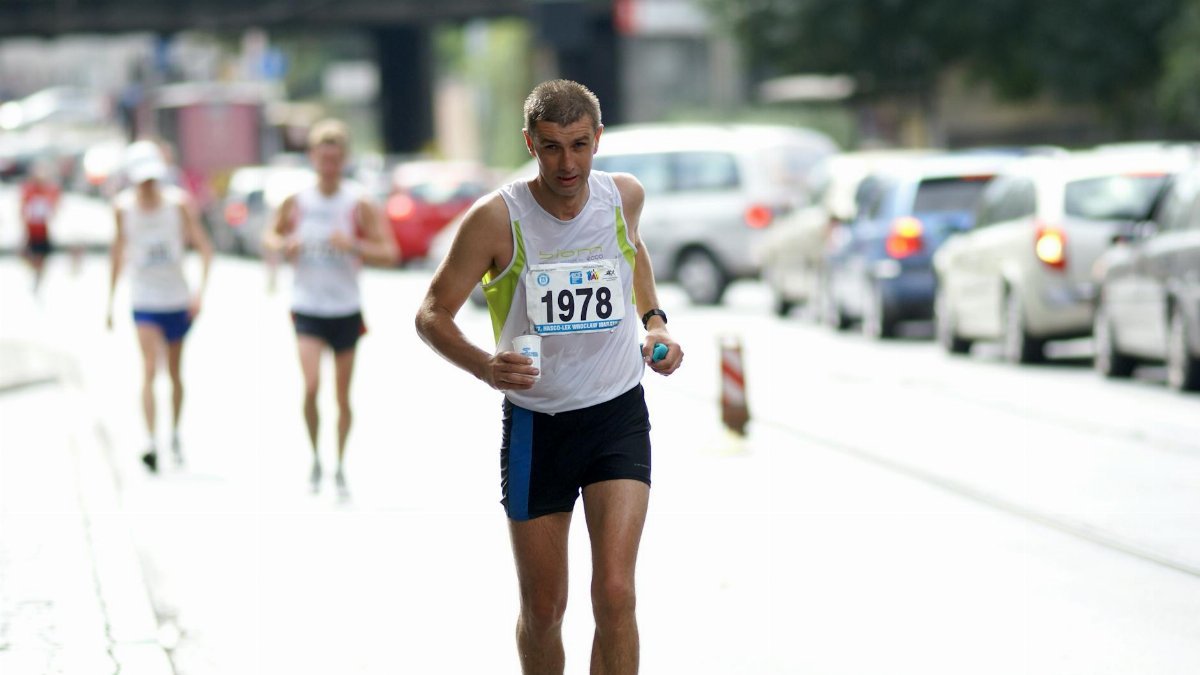 Focused adult running in a city marathon surrounded by traffic.