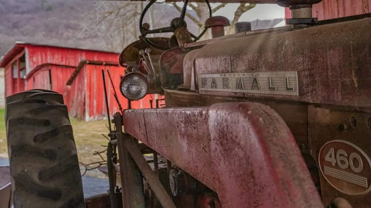Vintage Farmall 460 tractor parked in an old barn with red wooden walls in rural Pennsylvania.