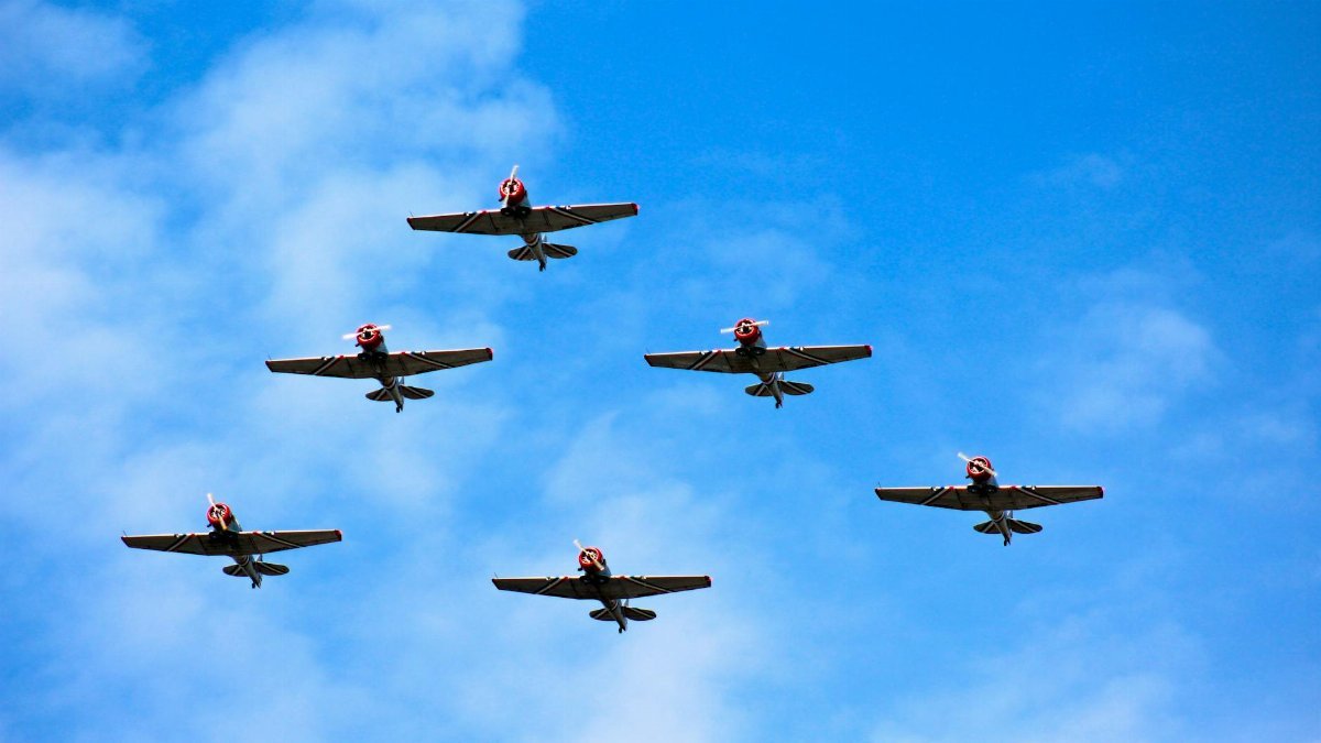 Six military airplanes flying in formation against a clear blue sky.