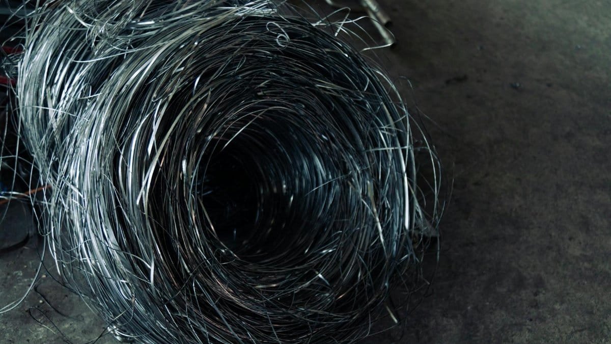 A roll of coiled metal wire in a factory setting, highlighting industrial textures.