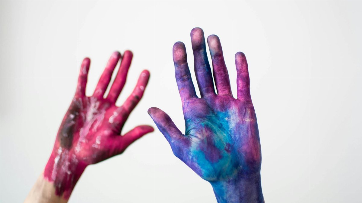 Vibrantly painted hands expressing artistic creativity against a neutral backdrop.