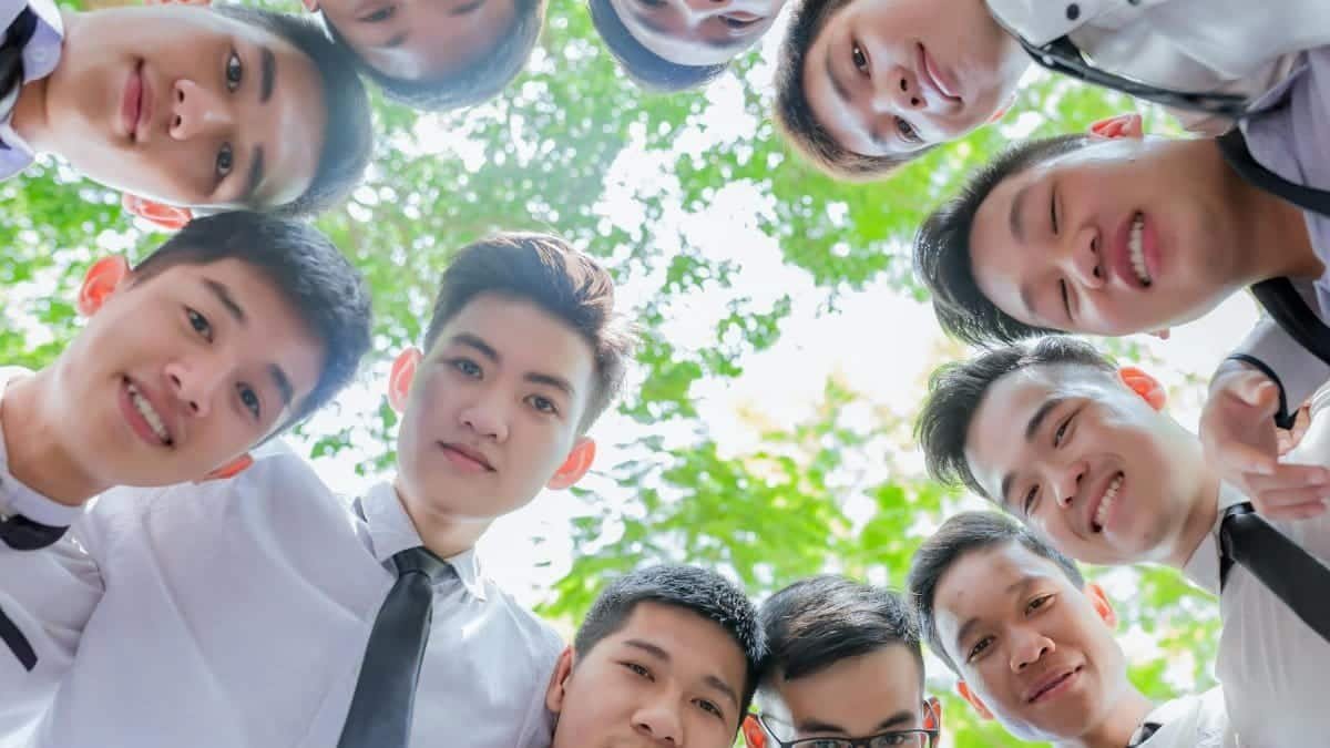 A group of young Asian men in formal attire smiling together outdoors in Huế, Vietnam.