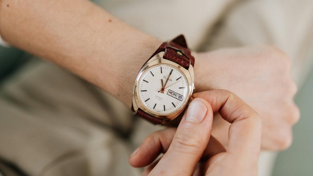 Detailed shot of a hand adjusting a wristwatch on the wrist, focusing on time setting.