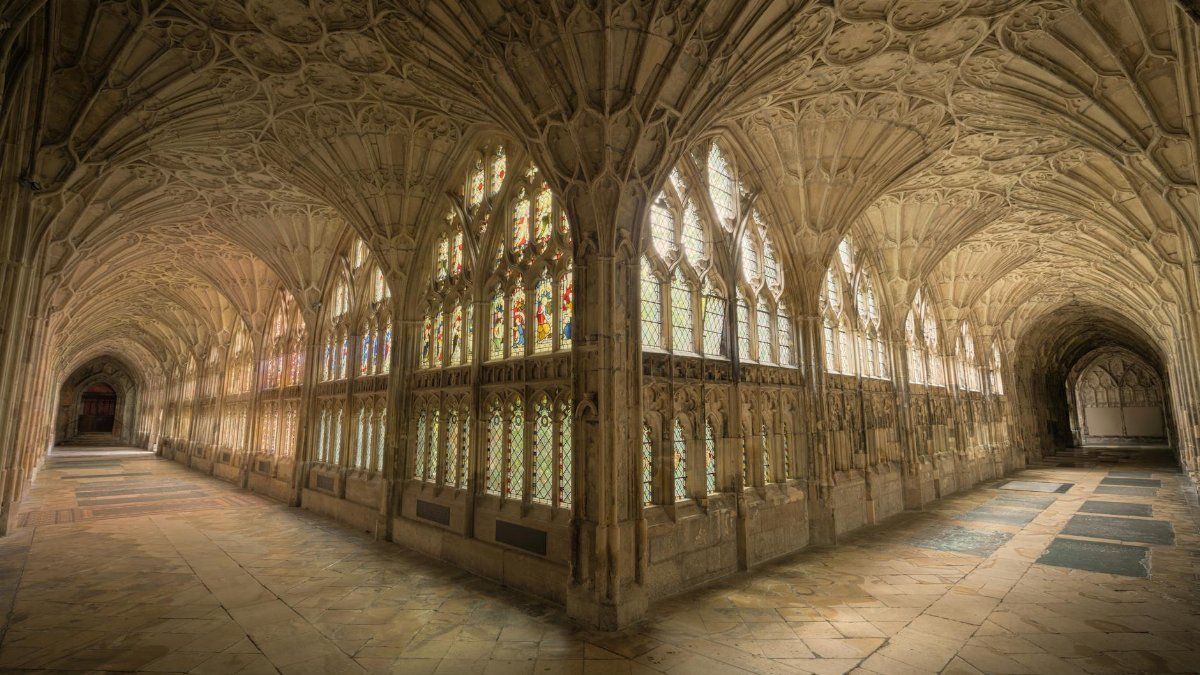 Intricate gothic cloisters with stained glass windows in Gloucester Cathedral, England.