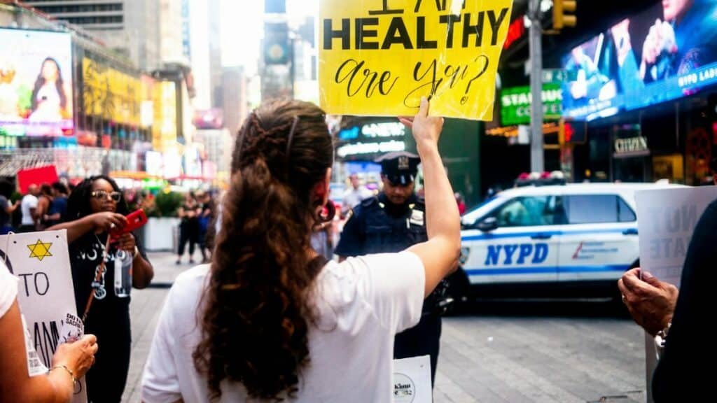 A protester holds a sign saying 'I Am Healthy, Are You?' in Times Square, New York City.