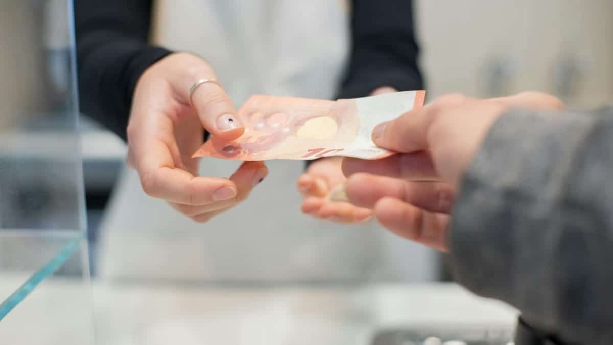 Close interaction of hands exchanging cash in a café setting. Business transaction detail.