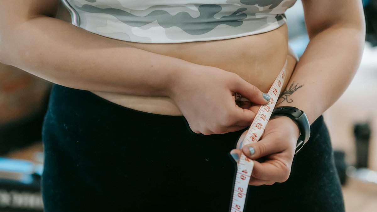 Close-up of a woman's waist being measured with a tape. Fitness and health concept.