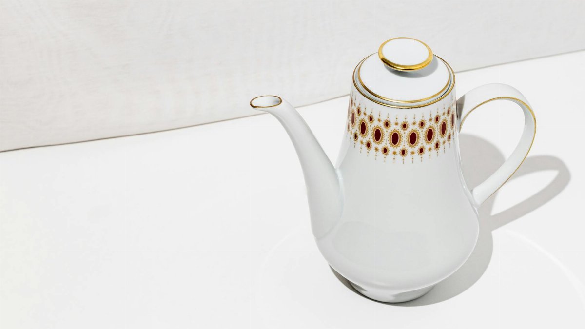 A classic white porcelain teapot with ornate design on a minimalist setting, ideal for tea-time imagery.