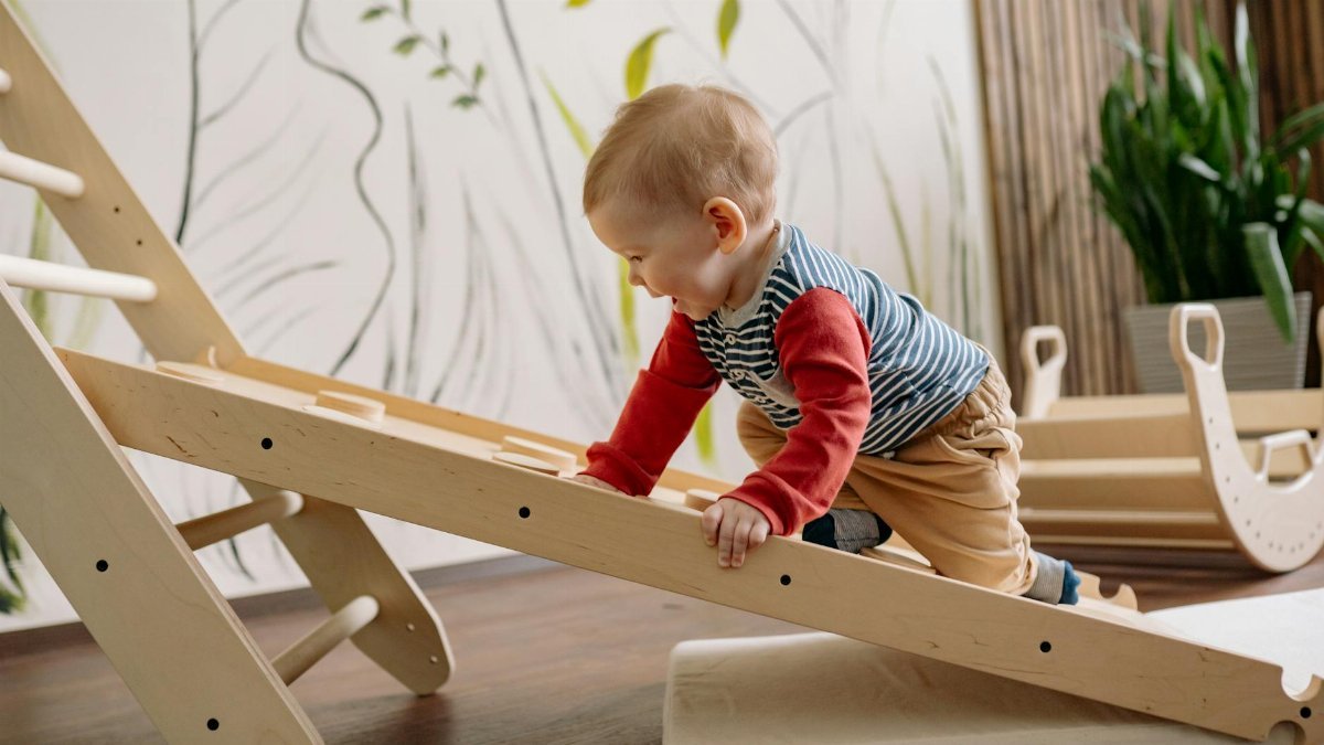 A young child enjoys climbing a wooden toy ladder indoors, promoting playtime and activity.