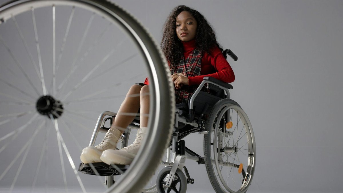 Portrait of a black woman with afro hair in wheelchair indoors.