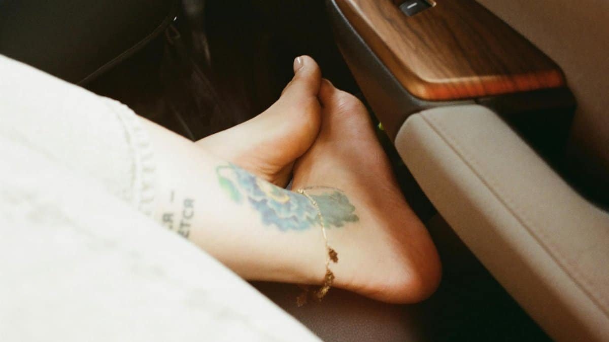 Relaxed view of bare foot with tattoo resting inside a car, cozy and laid-back vibe.