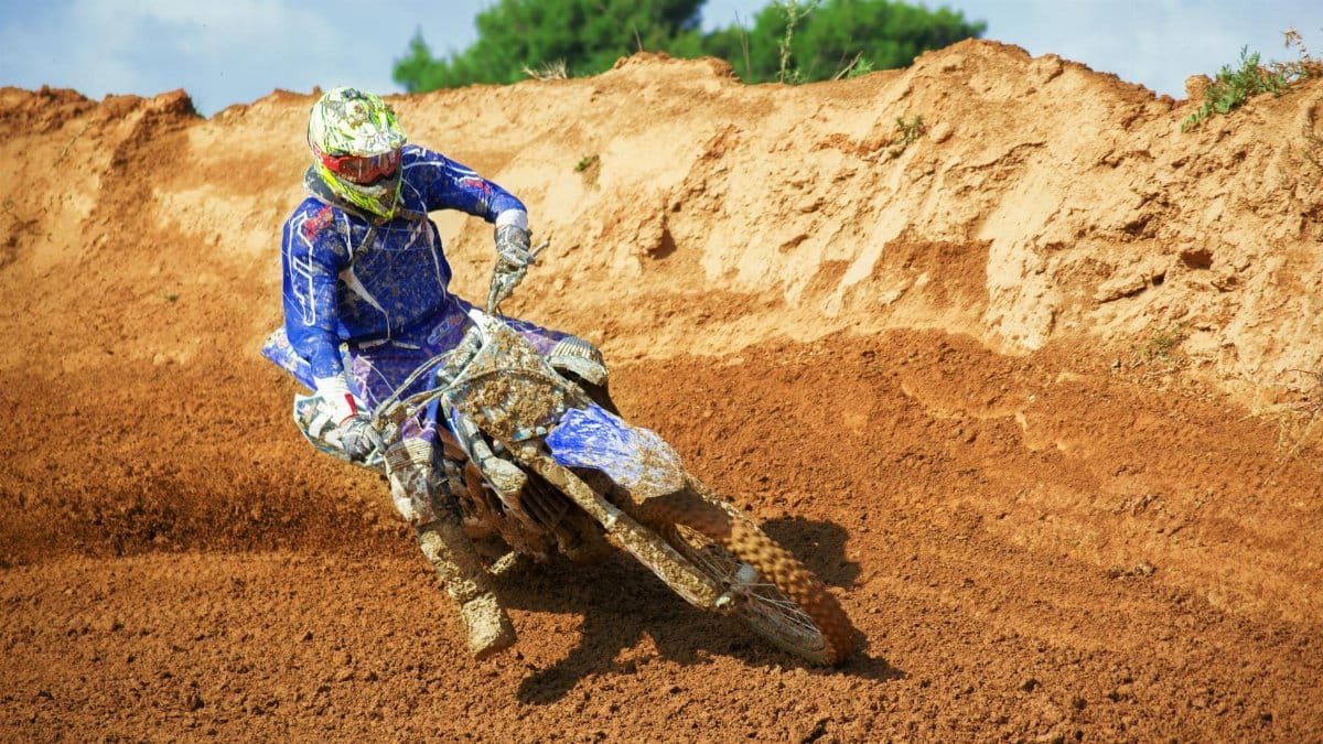 Dynamic motocross scene with a rider taking a sharp turn on a dirt track in Greece.