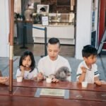A family of four shares ice cream together at an outdoor seating near an ice cream shop.