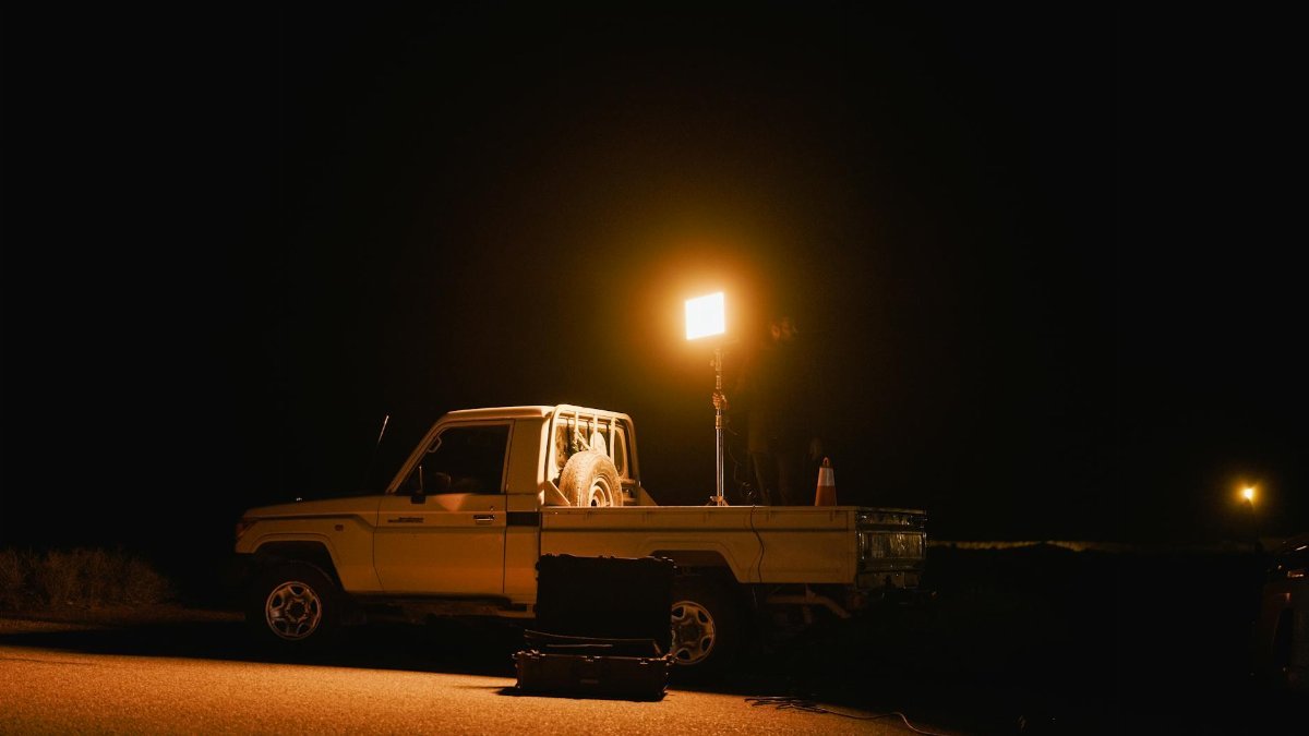 A white truck with a spotlight illuminating the road at night, creating a dramatic scene.