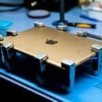 A close-up view of a tablet undergoing repair in a tech workshop with specialized tools.