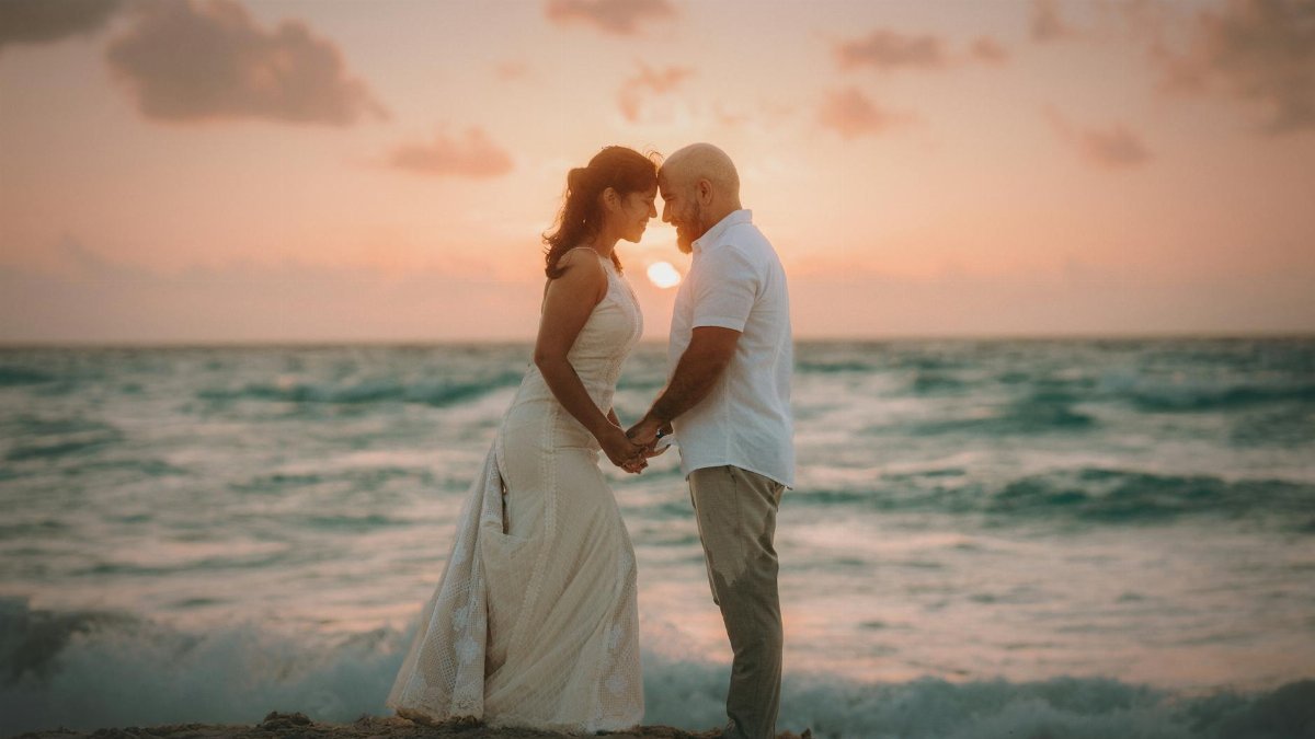 A couple embraces at sunset during a beach wedding in Costa Mujeres, Mexico.