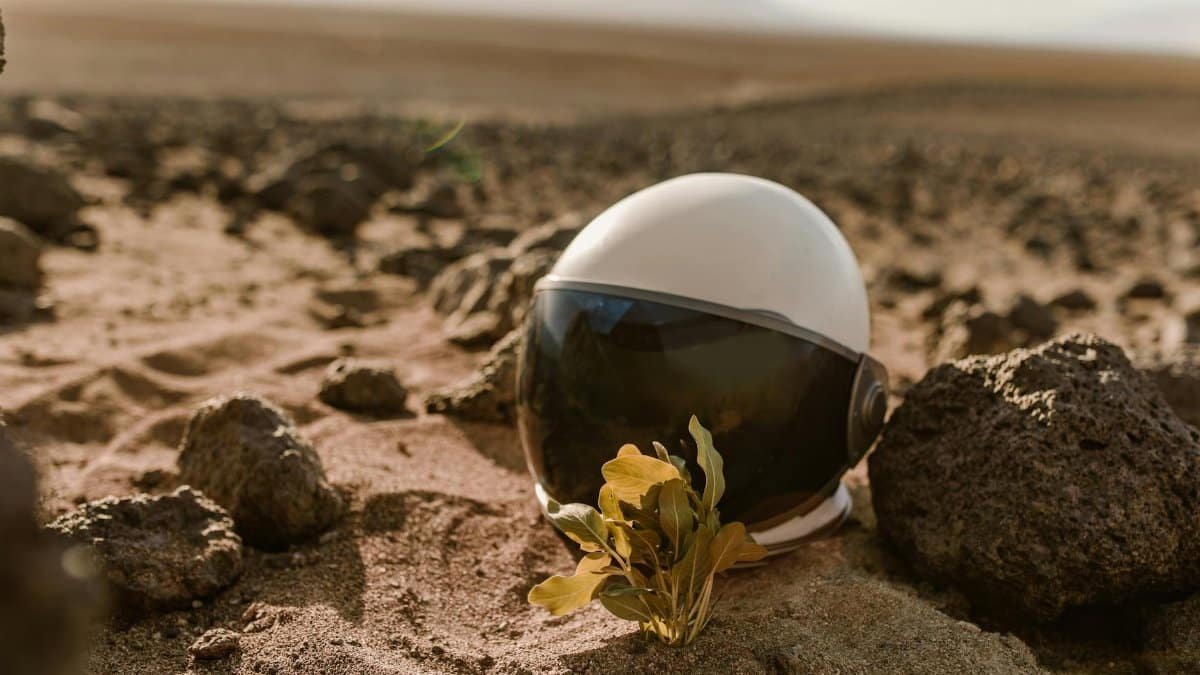 Close-up of an astronaut helmet on rocky desert terrain, evoking alien exploration.