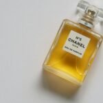 Elegant eau de parfum bottle with luxurious golden liquid on a minimalistic white background.