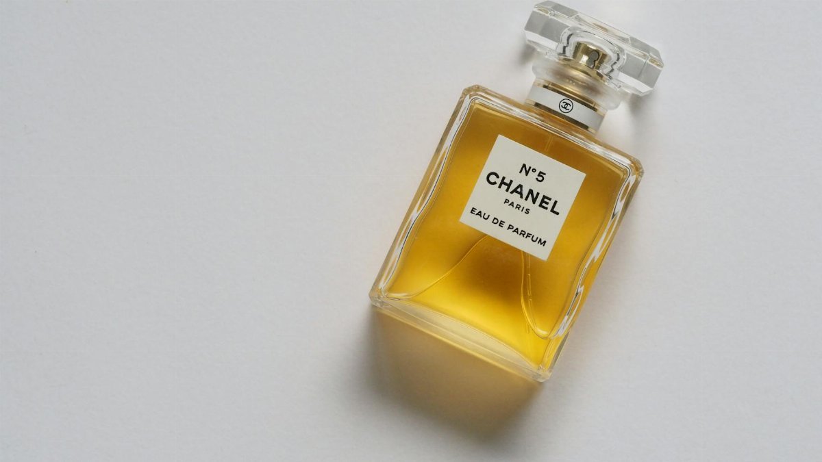 Elegant eau de parfum bottle with luxurious golden liquid on a minimalistic white background.