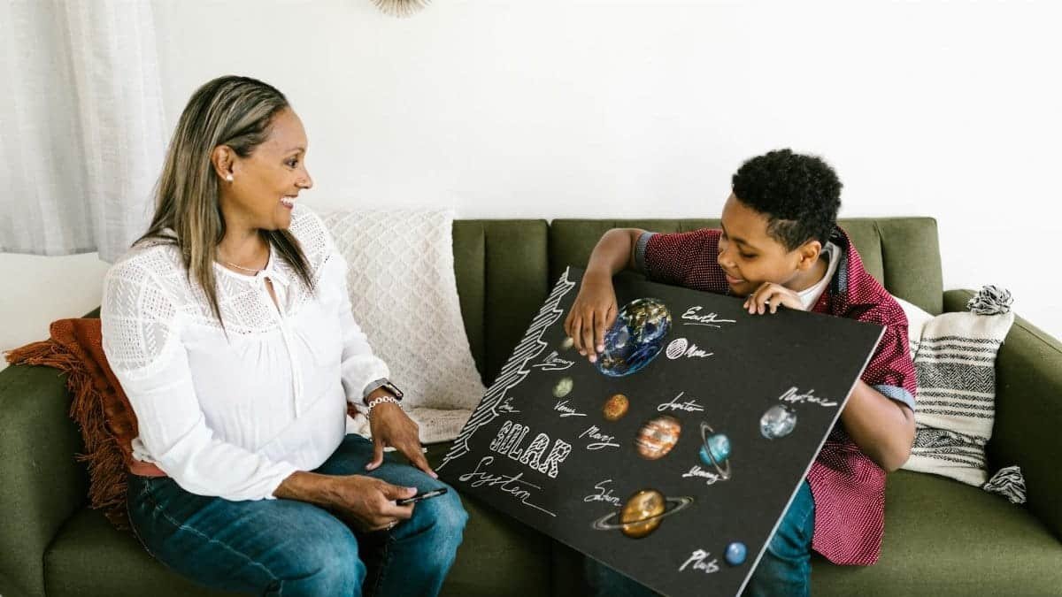 A woman and boy engage in a fun solar system project at home, enhancing learning and family time.