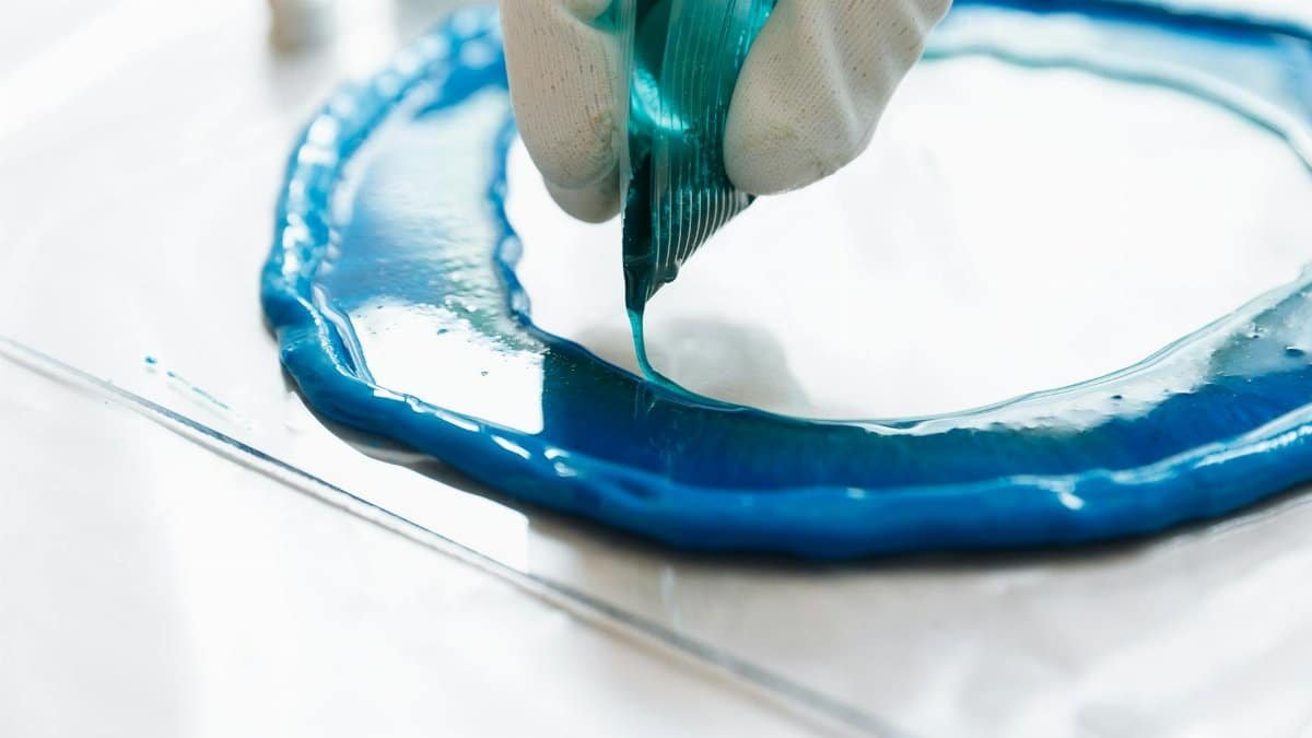 Detailed image of blue paint being applied in a circle by gloved hands, highlighting artistic process.