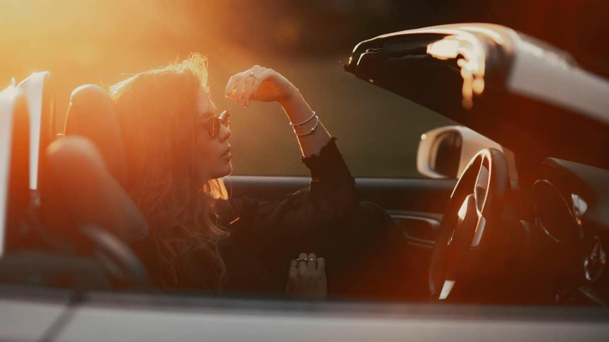 A woman enjoying a peaceful moment in a convertible during sunset.