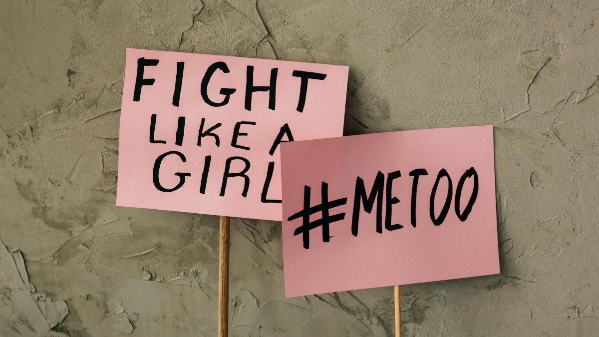 Pink protest signs with bold messages of feminism and empowerment on rough background.