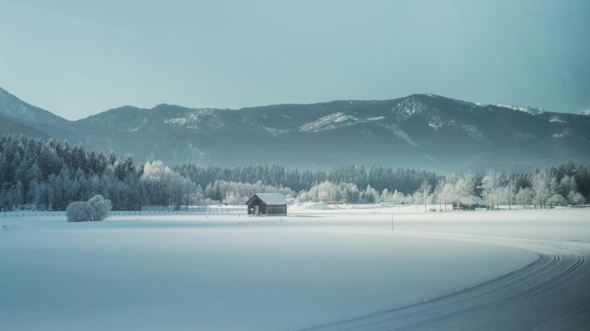Peaceful winter scene with a snow-covered cabin and mountain backdrop, ideal for calming visuals.