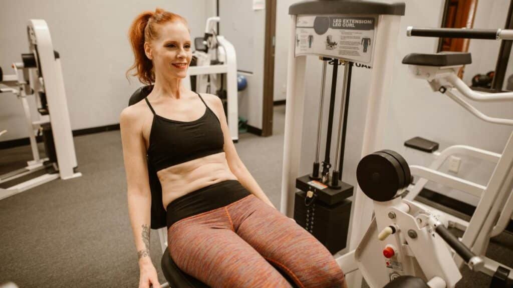 Woman performing leg workout in gym, showcasing fitness and health lifestyle.