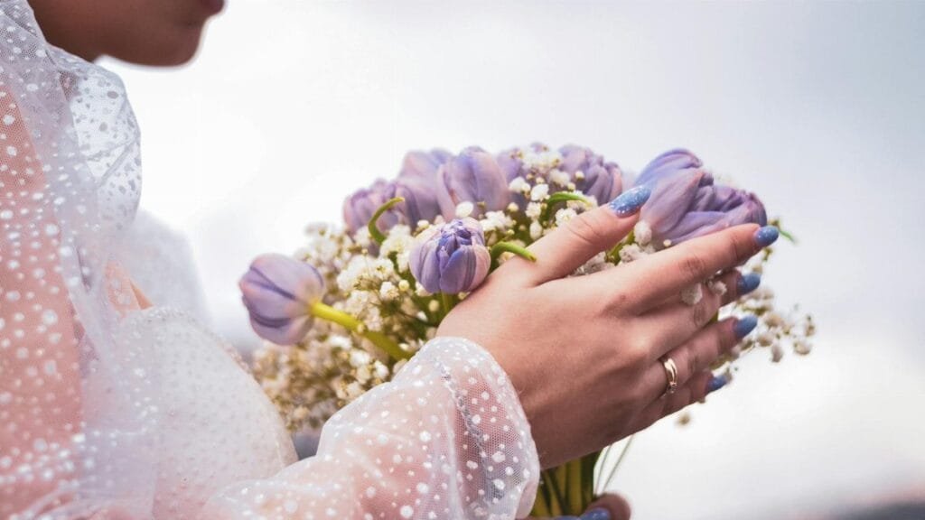 Woman holding a bouquet of purple tulips and baby's breath, showcasing delicate details.