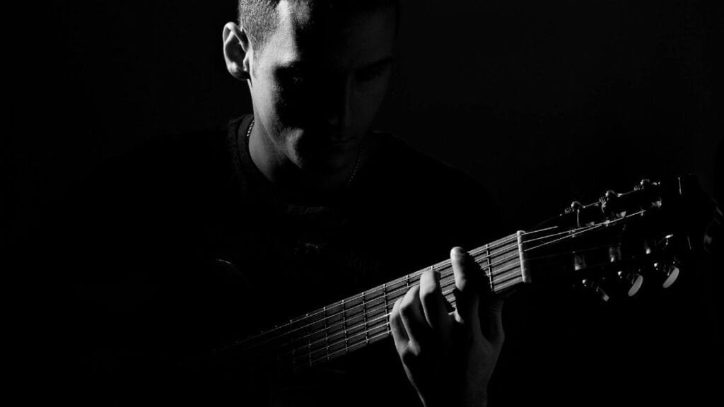 A captivating black and white portrait of a guitarist in an artistic pose, playing guitar.