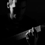 A captivating black and white portrait of a guitarist in an artistic pose, playing guitar.