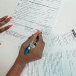 A woman with red nails fills out adoption application forms on a desk.