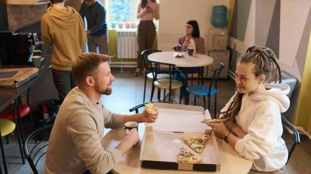 Colleagues enjoying pizza and coffee during a relaxed office lunch break.