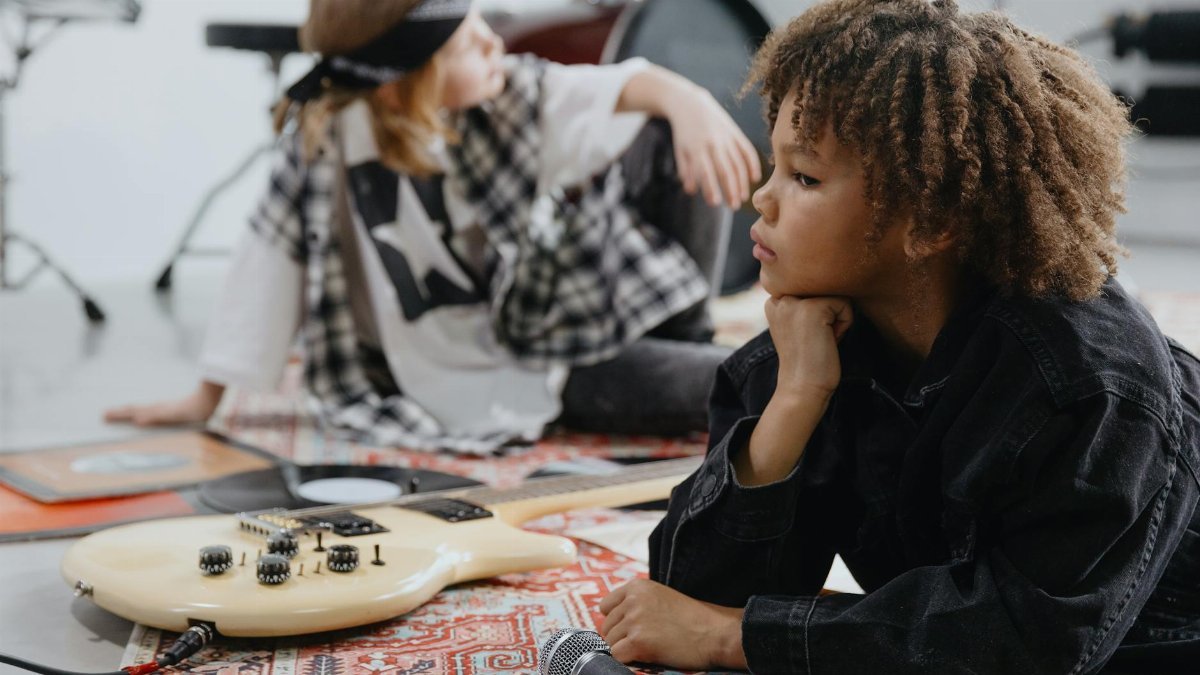 Two children engaging with musical instruments in an indoor setting, reflecting on music and creativity.