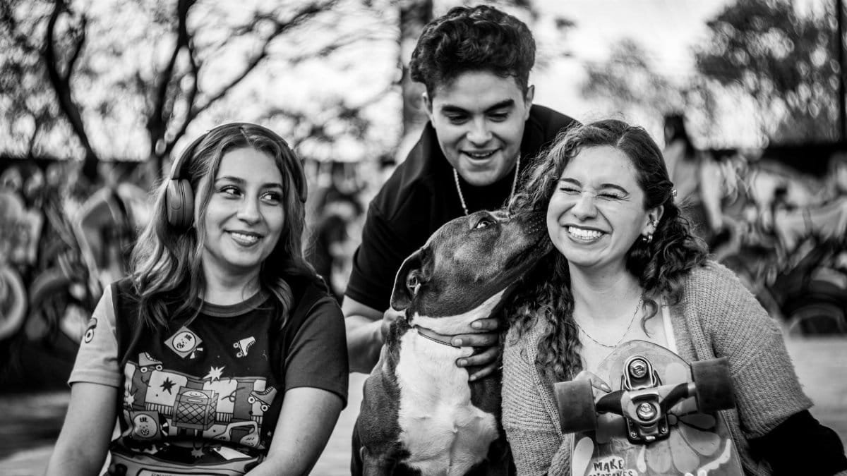 Group of friends sharing joyful moments with their dog in a park setting.