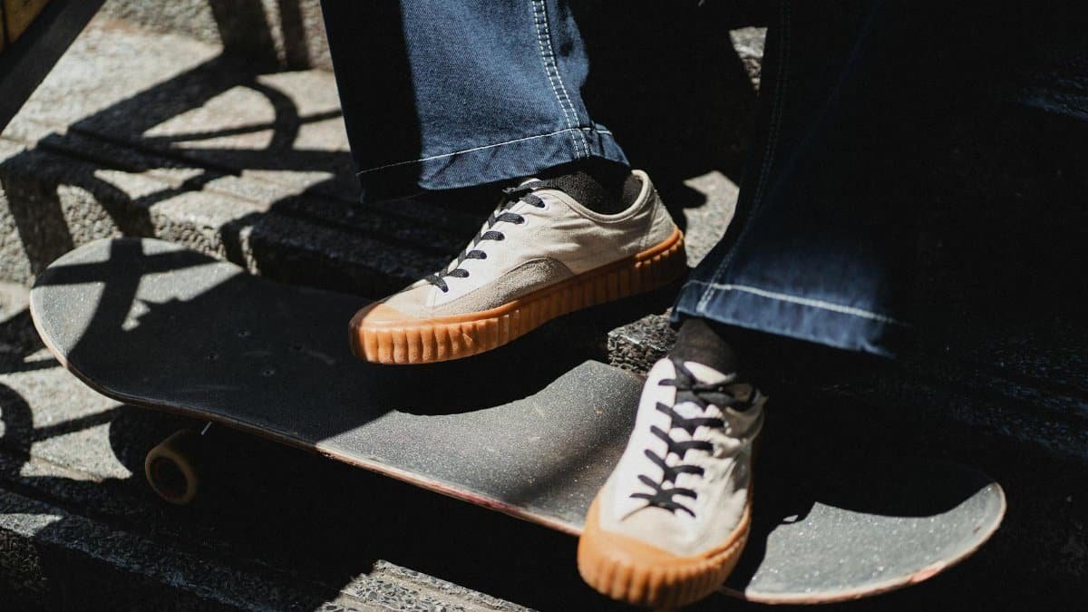 Close-up of sneakers resting on a skateboard on outdoor stairs.