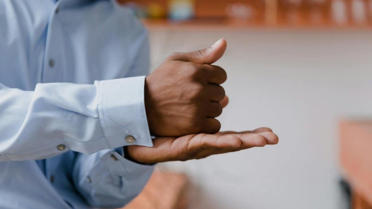 A man using sign language indoors with a focus on hand gestures and communication.