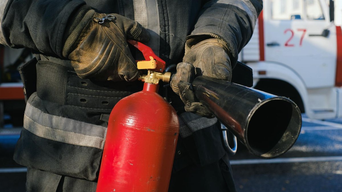 Firefighter in uniform holding a fire extinguisher, emphasizing safety and emergency readiness.
