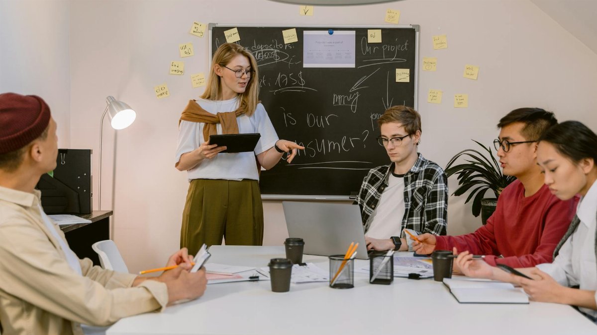 A diverse group of young professionals collaborating in a modern office setting with laptops and notes.