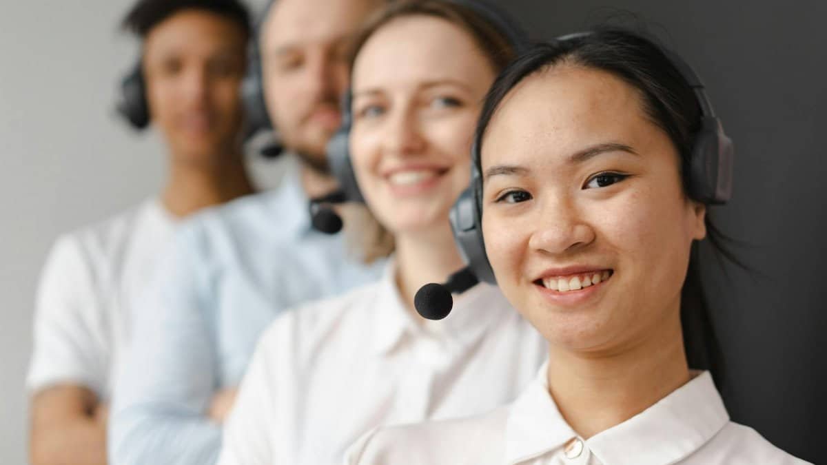 Smiling diverse team of customer support representatives wearing headsets, ready to assist.